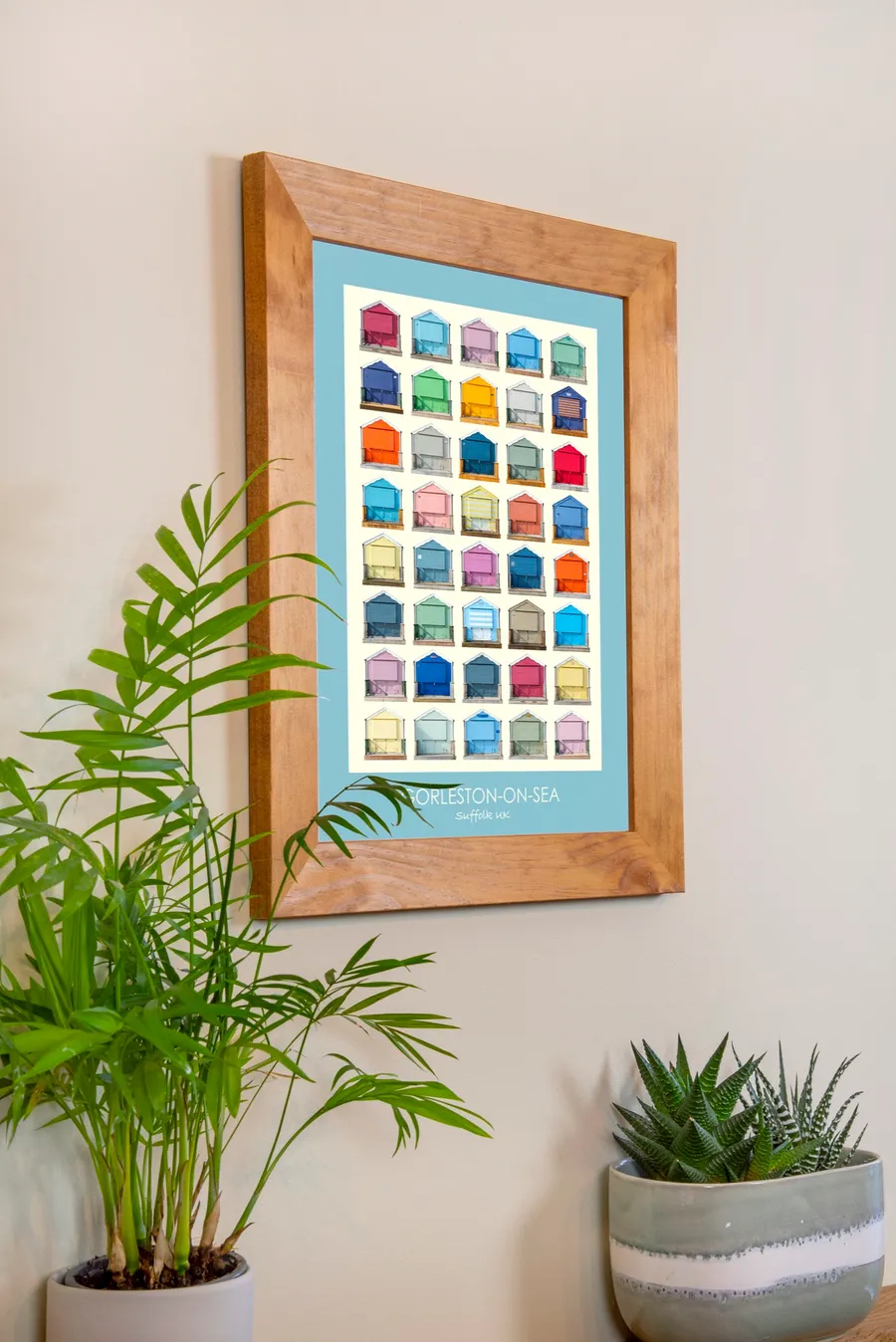 The same oak-framed Gorleston-on-Sea print seen from an angle, beside a palm