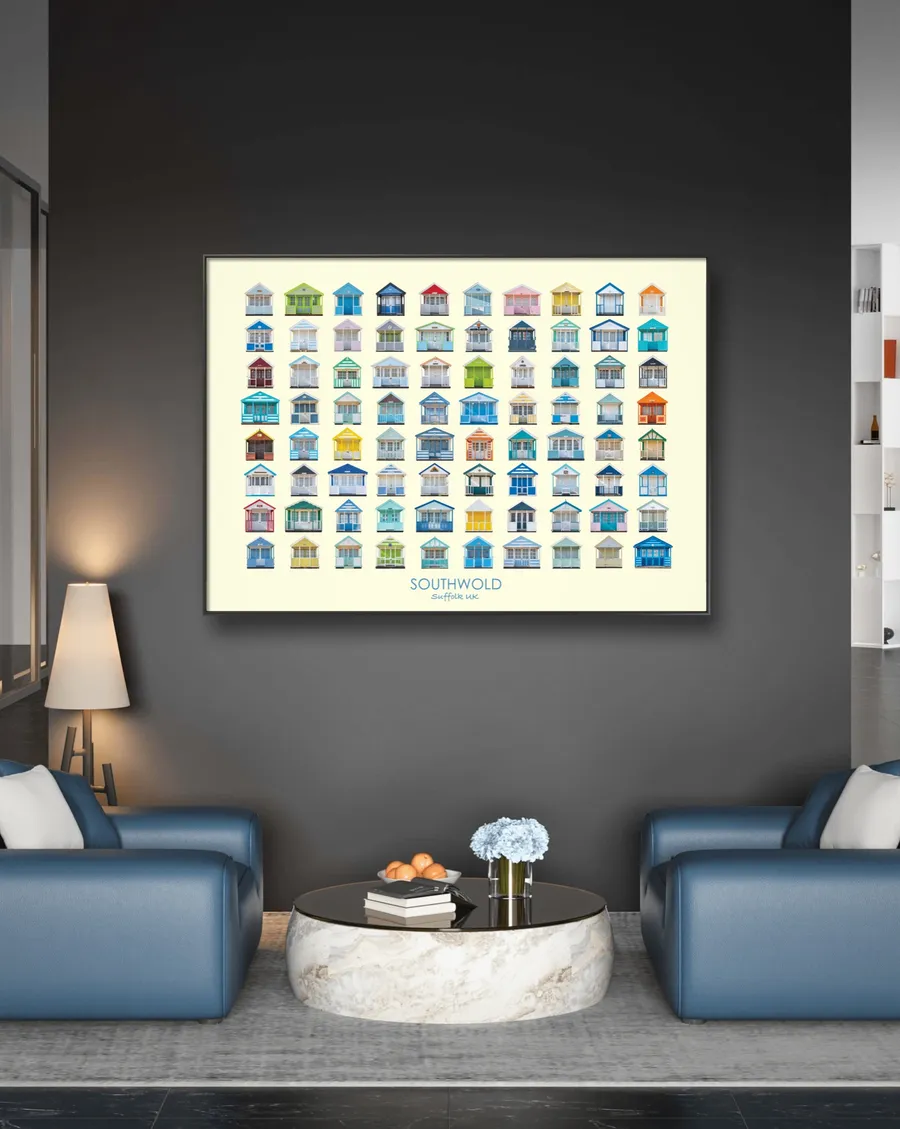 The landscape Southwold print in a black frame on a dark grey wall, above a round marble coffee table between two blue armchairs